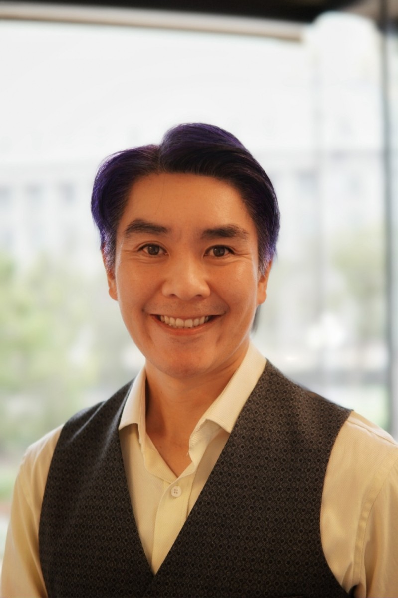 Headshot photo of SFE Director Tyrone Jue, who is wearing a brown vest with a buttoned white shirt