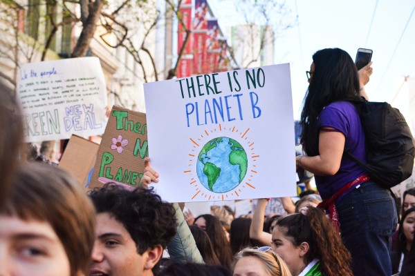 Youth activists holding signs at a rally that say "there is no planet B"